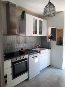 uma cozinha com armários brancos, um fogão e um lavatório em La VILLA Luchonaise em Luchon