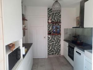 una cocina con armarios blancos y encimeras negras en La VILLA Luchonaise, en Luchon