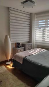 1 dormitorio con cama, lámpara y ventanas en Acogedor apartamento playa Usil a 600 m de la playa en Mogro