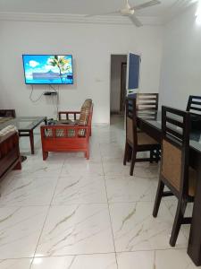 ein Wohnzimmer mit Stühlen und einem TV an der Wand in der Unterkunft TOTSI New World in Lomé