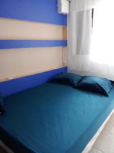 a blue bed in a room with a window at Le Caferoom Club in Tsingoni