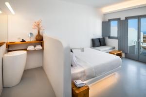 a white bedroom with a bed and a chair at Alunia Incognito Suites - Adults Only in Pyrgos
