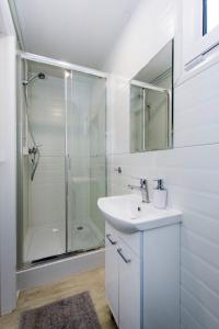 a white bathroom with a sink and a shower at Villa Dzika Plaża in Gdańsk