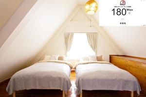 two beds in a attic room with a window at にらい恩納 伊集 in Onna