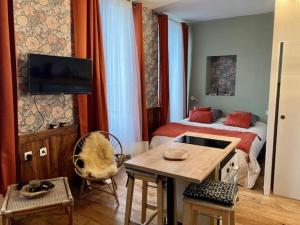 a bedroom with a bed and a table and a tv at Une maison de famille in Oloron-Sainte-Marie