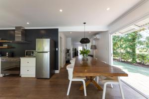 a kitchen with a wooden table and a refrigerator at Nala Cottage at Patonga in Patonga Beach