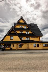 ビャウィ・ドゥナイェツにあるŚleboda wynajem pokoi Ewa Satołaの黒屋根の大きな黄色の建物