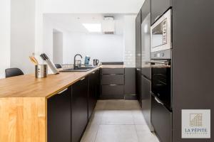 een keuken met zwarte kasten en een houten aanrecht bij Atelier 46 - Appartement 2 chambres. in Valenciennes