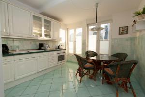 - une cuisine avec des placards blancs, une table et des chaises dans l'établissement Villa Meerblick Warnemünde - Ferienwohnung mit Meerblick in erster Reihe zum Strand und Promenade, à Warnemünde