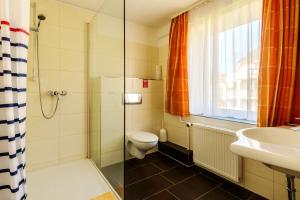 a bathroom with a shower and a toilet and a sink at Hotel Störtebeker in Graal-Müritz