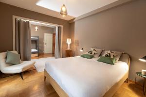 a bedroom with a large white bed and a chair at La VILLA du Reims in Colmar