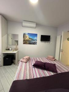 1 dormitorio con cama, lavabo y TV en b&b La Rosa dei venti en Alassio