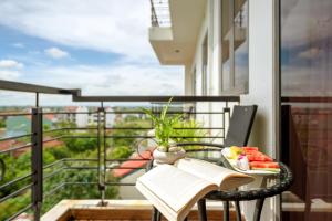 a table with a book and a bowl of fruit on a balcony at Athenia Hoi An Boutique Hotel & Spa in Hoi An