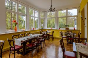 ein Restaurant mit Tischen und Stühlen in einem Zimmer mit Fenstern in der Unterkunft Hotel Störtebeker in Graal-Müritz
