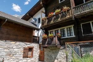 ein altes Gebäude mit Blumenkästen auf dem Balkon in der Unterkunft Incanto Walser Apartments Ronco in Macugnaga