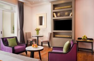 una camera d'albergo con sedie viola e TV di Memoire Palace Resort & Spa a Siem Reap