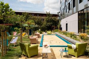 - un jardin avec des chaises et une piscine dans un bâtiment dans l'établissement Moxy Paris Val d'Europe, à Montévrain