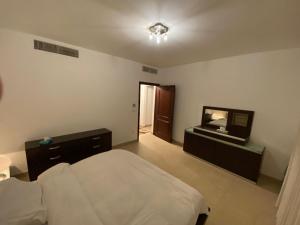 een slaapkamer met een bed, een dressoir en een spiegel bij Lovely first floor tow bed rooms overviewing circular pool in Talabay Aqaba in Aqaba