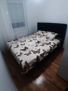 ein Bett mit einer Tagesdecke mit Schmetterlingen darauf in der Unterkunft Apartman City BL in Banja Luka