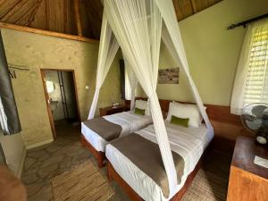 a bedroom with two beds with mosquito nets at Sambiya River Lodge in Murchison Falls National Park