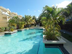 a swimming pool with palm trees in front of a building at Little Venice villas in Flic-en-Flac