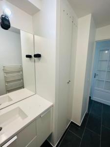 Élégant appartement Paris 6ème في باريس: حمام أبيض مع حوض ومرآة