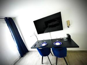 - une table noire avec des chaises bleues dans la chambre dans l'établissement T1 - Le paille en queue - neuf, vue jardin, 11min aéroport, à Saint-Denis