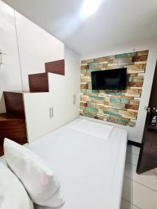 a bedroom with a brick wall with a tv on it at Dasma Lofts Hotel near Dela Salle Dasma in Dasmariñas