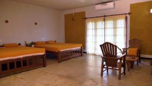 馬圖格默的住宿－Manikgoda Tea Paradise，一间卧室设有两张床、一把椅子和一个窗户。