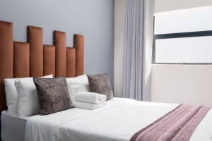 um quarto com uma cama grande com lençóis brancos e almofadas em Cape palm royal guest house em Cidade do Cabo