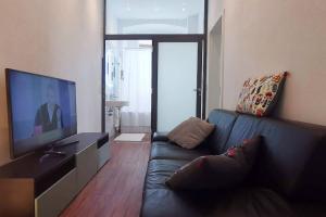 a living room with a black couch and a flat screen tv at 3,5 Z-Wohnung, 2 Schlafzimmer für 4 Personen, 30 Min Zürich in Klettgau