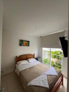 um quarto com uma cama grande e uma janela em Cómoda casa en condominio para descansar em Ricaurte