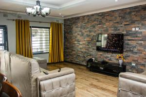 a living room with couches and a tv and a brick wall at Stay Simple Lodge in Lusaka