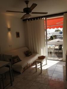 un soggiorno con divano e ventilatore a soffitto di EL CHAPARRAL Studio-appartement with fantastic pool view and STRONG WIFI a Costa Del Silencio