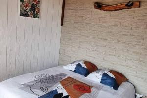 Cama en habitación con pared de ladrillo en Bungalow des pensées piscine chauffée 28° en Saint-Denis