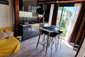 a kitchen with a table and two stools in a room at Bungalow des pensées piscine chauffée 28° in Saint-Denis