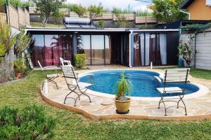 um pátio com 2 cadeiras e uma piscina em Bungalow des pensées piscine chauffée 28° em Saint-Denis