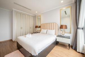 1 dormitorio con 1 cama blanca grande y espejo en Vera Saigon Apartments - Vinhomes Central Park, en Ho Chi Minh