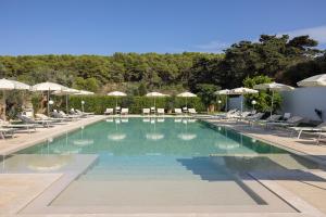 a large swimming pool with chairs and umbrellas at Masseria Bandino & Spa in Otranto