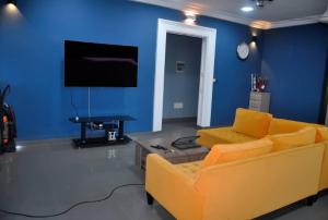 a living room with a yellow couch and a blue wall at Résidence Sampo in Ouagadougou