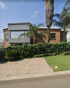 a brick house with a palm tree in front of it at Tshidiso Guesthouse in Centurion