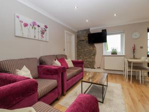 a living room with a purple couch and a table at Myrtle Cottage in Cardiff