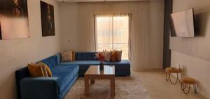 a living room with a blue couch and a table at Appartement gueliz de luxe in Marrakesh