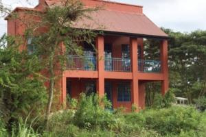 een groot rood huis met een balkon aan de zijkant bij Gongali House - Karatu Rewilded in Karatu