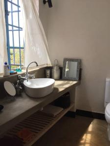 een badkamer met een witte wastafel en een raam bij Gongali House - Karatu Rewilded in Karatu
