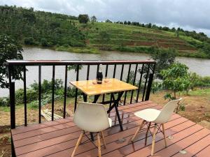 een tafel en twee stoelen op een houten terras met een rivier bij The FARM on the LAKE in Di Linh