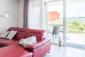 a red couch in a living room with an umbrella at Haus Seeblick Wohnung 14 in Wohlenberg