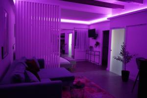 - un salon avec un éclairage violet et un canapé dans l'établissement Secret Garden Vendégház, à Pécs