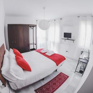Palacio de Dueñas Private Terrace في إشبيلية: غرفة نوم بسرير ومخدات حمراء وتلفزيون
