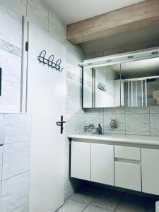 ein weißes Badezimmer mit einem Waschbecken und einem Spiegel in der Unterkunft Casa Lilly - CharmingStay in Flumserberg